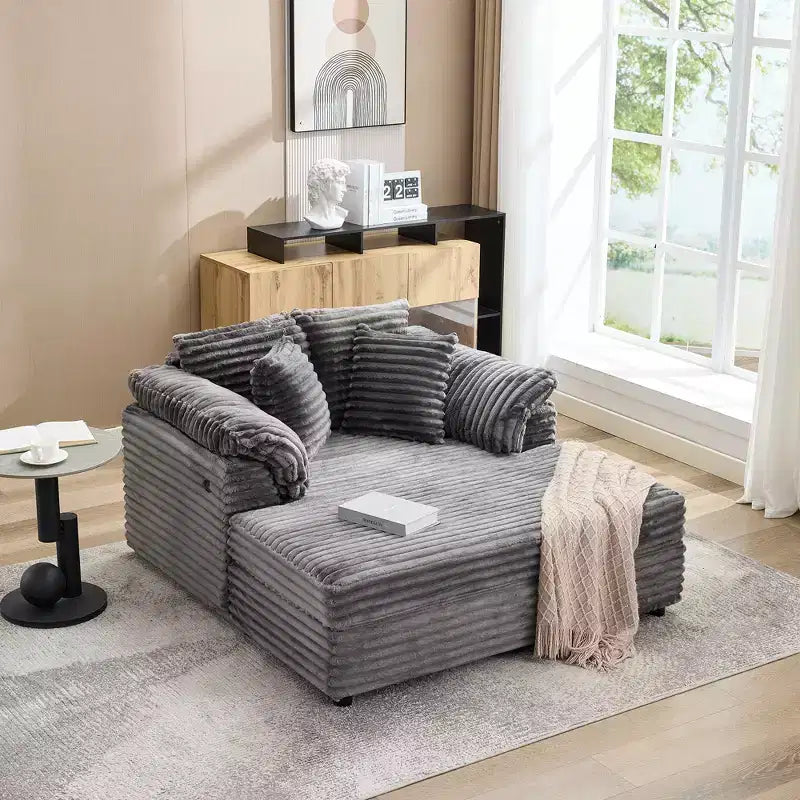 Poltrona chaise longue oversize da interno, comodo divano lounge in velluto a coste con ampi braccioli imbottiti e cuscini decorativi, accogliente divano letto per soggiorno